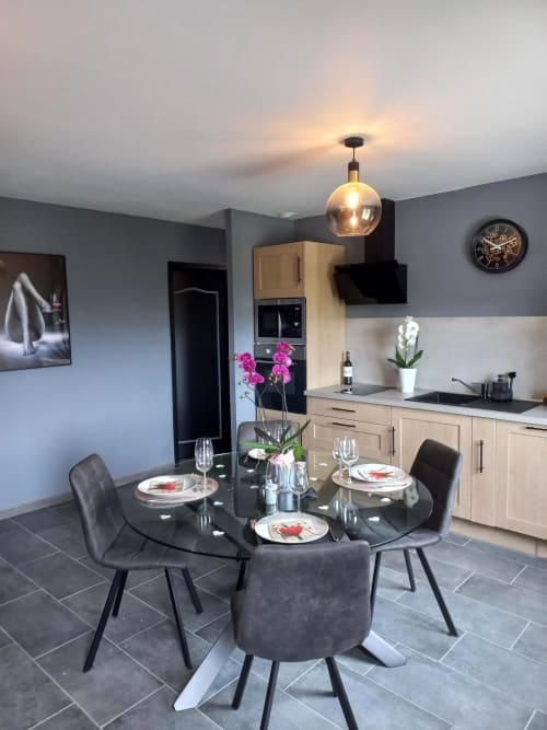Salle à manger et cuisine moderne à La Maison du Plaisir avec table ronde noire, mise de table élégante et design contemporain