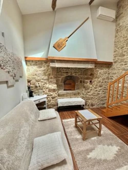 Rustic stone bedroom at Logis De La Bénétière with fireplace, wooden beams, and traditional French decor in Treize-Vents