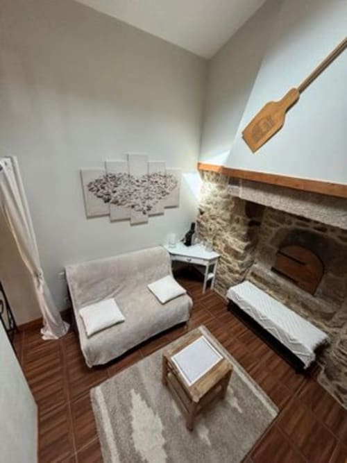 Chambre la Chouanne lounge area with fireplace, white upholstered furniture, wooden oar décor at Logis De La Bénétière,