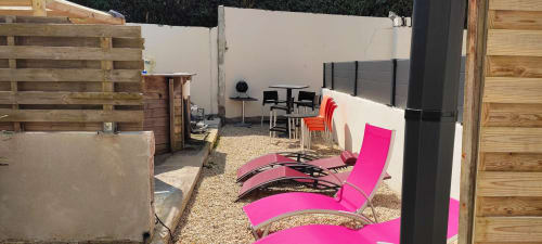 Transats roses sur la terrasse en gravier de la Résidence des dunes, gîte à Landéda, avec terrasse en bois et mobilier