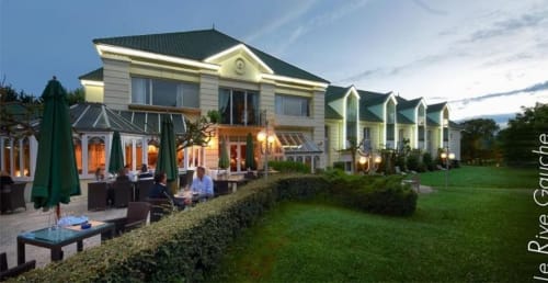 Le Prieuré Du Preux elegant manor house with outdoor terrace, green umbrellas, and manicured gardens at dusk in Sépeaux Saint