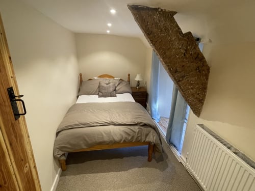 Exposed beams feature windows guest bedroom in large historic farmhouse group stay accommodation