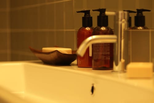 Bathroom amenities at New Oporto Apartments in Porto featuring pump bottles, soap dish, and faucet on sink