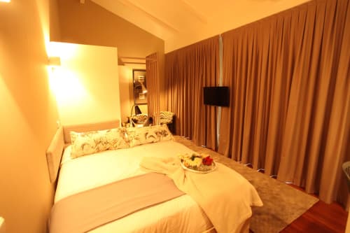 Warm-lit bedroom at New Oporto Apartments in Porto with queen bed, patterned pillows, flat-screen TV, and floor-to-ceiling