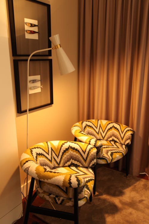 Cozy apartment seating area at New Oporto with patterned yellow chairs, floor lamp, and framed art on warm-toned walls.