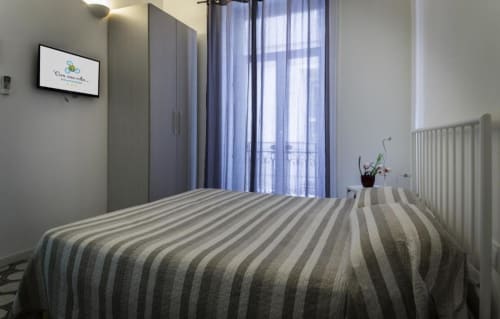 Deluxe double room at C'era una Volta in Palermo with striped bed, garden view balcony, flat-screen TV, and modern amenities.