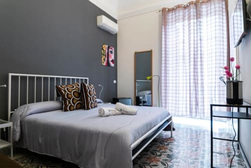 Camera moderna presso C'era una Volta B&B a Palermo con parete d'accento grigia, letto bianco in metallo e tende a quadri