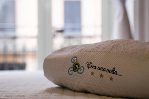 C'era una Volta Palermo bed pillow with decorative embroidery and Italian text, city view balcony backdrop