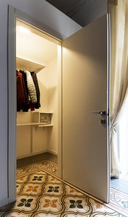 Elegant walk-in closet in C'era una Volta's Deluxe Quadruple Room, Palermo, with warm lighting and decorative tile floor.