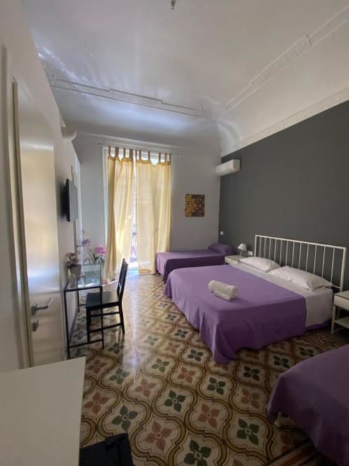 Deluxe Quadruple Room at C'era una Volta, Palermo - twin beds with purple linens, garden view, white ceilings