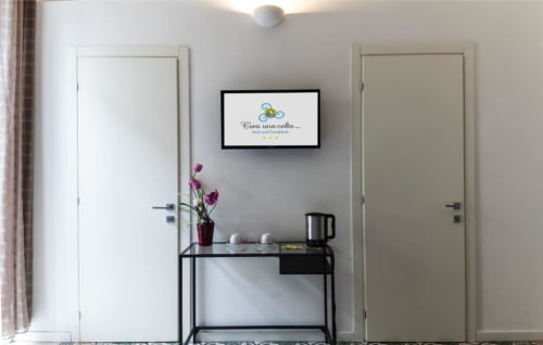 C'era una Volta B&B Palermo Deluxe Triple Room entryway with TV, welcome desk, purple flowers, and clean modern design