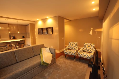 Superior Apartment living area at New Oporto Apartments, Porto, with gray sofa, patterned armchairs, and open kitchen