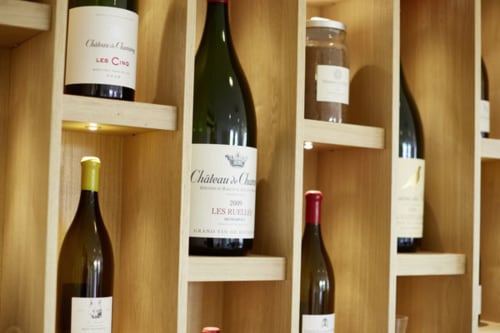 Wine bottles displayed in wooden wine rack at Les Maisons de Chamirey, a Mercurey wine country bed and breakfast in France