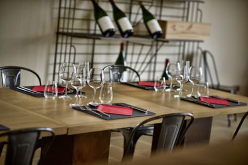Elegant dining setup at Les Maisons de Chamirey with wine glasses, place settings, and wine bottles on shelf in Mercurey.