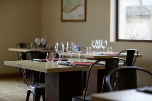 Elegant dining room at Les Maisons de Chamirey in Mercurey with set table, wine glasses, and black chairs