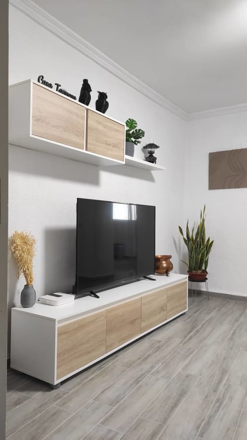 Sala de estar moderna en Casa Torrens con TV montada en pared, muebles de madera, plantas en maceta y decoración minimalista