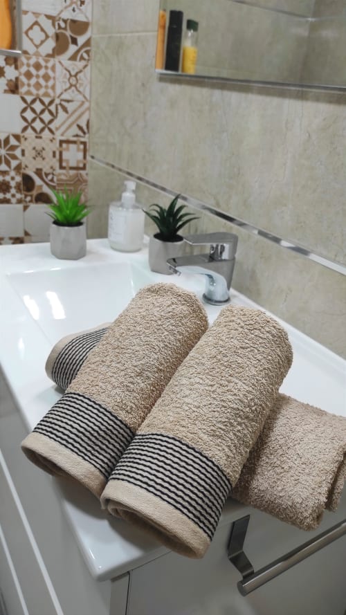 Toallas beige con franjas negras en el lavamanos del apartamento Casa Torrens Mar y Montaña, Polop de la Marina