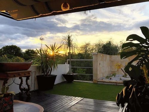 Terraza en azotea de Alojamientos Zoogocho con vista al atardecer, plantas en macetas, piso de madera y paisaje exuberante en San Andrés