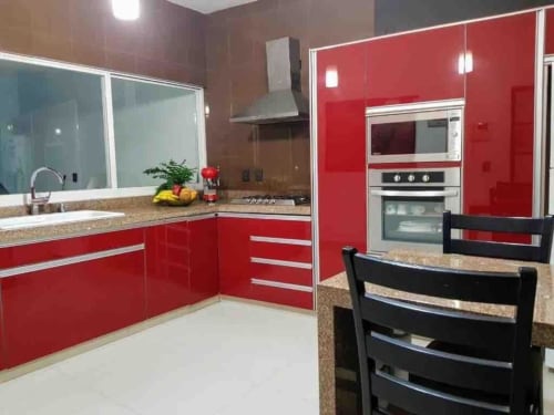 Cocina moderna roja y blanca en villa Zoogocho Boutique House con electrodomésticos de acero inoxidable y encimeras de granito