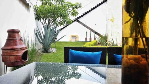 Terraza al aire libre con asientos tapizados en azul, chimenea de barro y exuberante jardín en la villa Zoogocho Boutique House en San Andrés