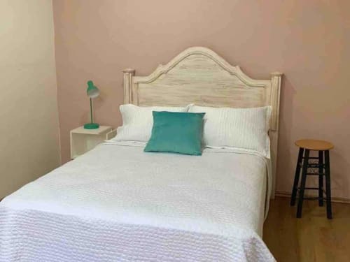 Dormitorio luminoso en la cabaña Casa Palmeras de Oaxaca con cabecero de madera crema, ropa blanca, almohada turquesa y detalles verdes