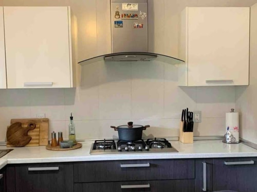 Cocina moderna en la cabaña Casa Palmeras con estufa de gas, gabinetes oscuros, encimeras blancas y campana extractora de acero inoxidable