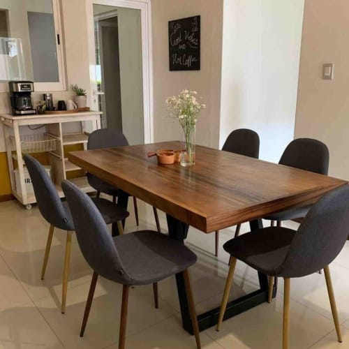 Comedor de la cabaña Casa Palmeras con mesa de madera, sillas negras, flores y cocineta al fondo, Oaxaca México