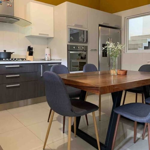 Cocina y comedor modernos en la cabaña Casa Palmeras con mesa de madera, sillas oscuras y electrodomésticos de acero inoxidable