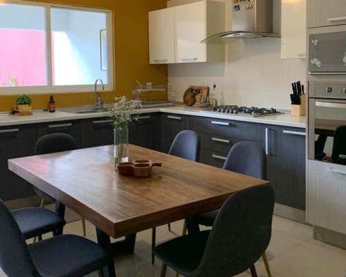 Moderna cocina y comedor de la cabaña Casa Palmeras en Oaxaca con mesa de madera, sillas negras y electrodomésticos de acero inoxidable