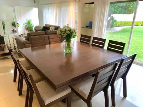 Amplio comedor con mesa y sillas de madera, sala con sofá marrón y grandes ventanales con vistas al jardín en Casa