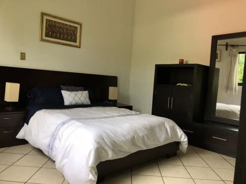 Modern bedroom with black furniture and white bedding at El Nogal House in San Andrés Huayapam