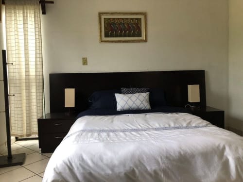Modern bedroom in El Nogal House at Alojamientos Zoogocho with black headboard, white bedding, and natural light from
