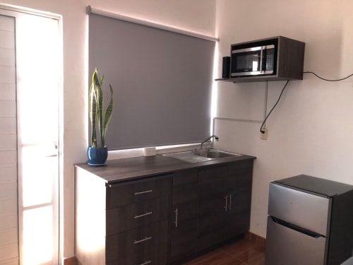 Moderna cocineta en el Departamento Zeus 12 de Alojamientos Zoogocho con microondas, fregadero, estufa, refrigerador y televisor montado
