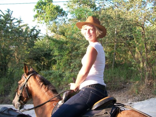 Woman horseback riding on trail surrounded by lush forest at Villa Mango B&B in Nosara, Costa Rica