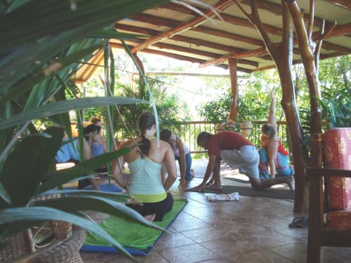 Yoga class at Villa Mango B&B in Nosara, guests practicing on mats under tropical wooden pergola