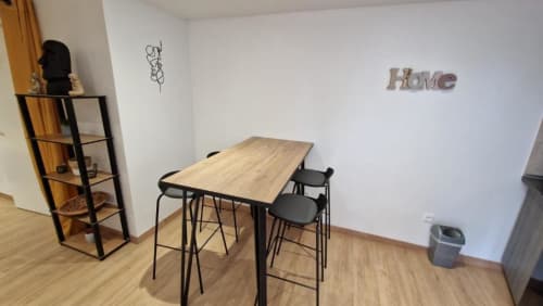 Kitchenette moderne avec table à manger, tabourets noirs, parquet et décoration murale 'Home'