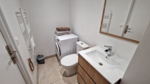 Salle de bain moderne avec lavabo, toilettes, lave-linge et sèche-serviettes chauffant à l'appartement Pont-Sainte-Maxence