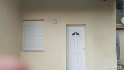 Entrée extérieure d'appartement avec porte blanche, fenêtre à volets et murs crème à Pont-Sainte-Maxence