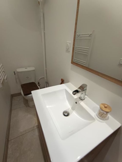 Salle de bain moderne et épurée avec lavabo blanc, toilettes et radiateur-sèche-serviettes à l'appartement de Pont-Sainte-Maxence