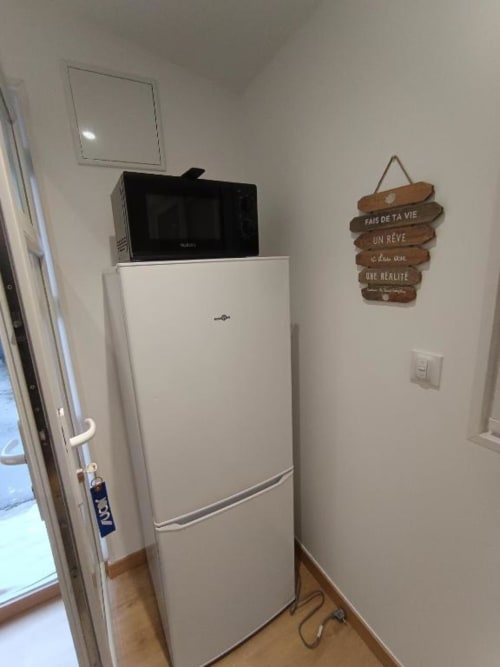 Coin cuisine avec réfrigérateur blanc, micro-ondes et panneau motivationnel en bois dans l'appartement de Pont-Sainte-Maxence