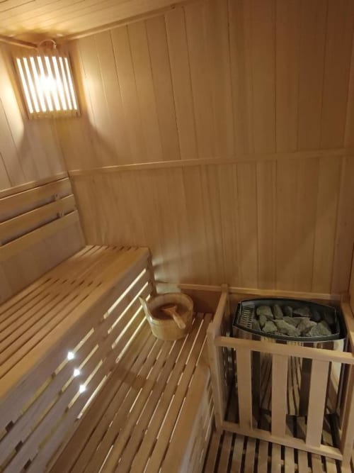 Intérieur de sauna en bois avec bancs, poêle et fenêtre à la villa de Pont-Sainte-Maxence