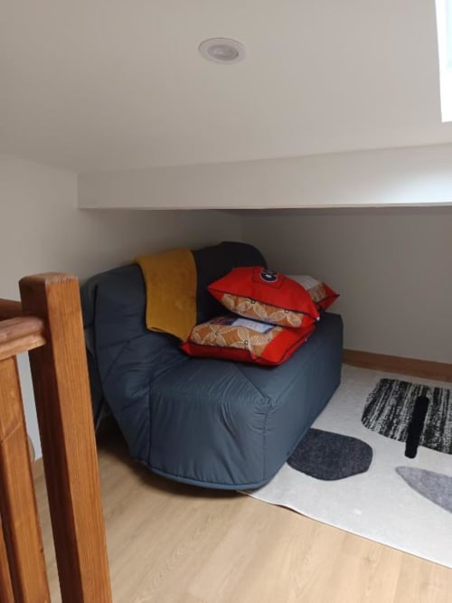 Fauteuil poire bleu foncé avec coussins colorés et plaid dans la chambre de la villa à Pont-Sainte-Maxence