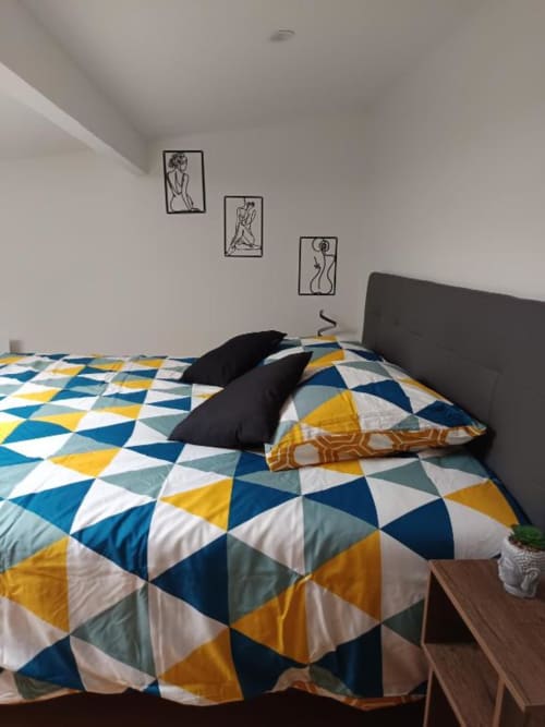 Chambre de villa avec literie géométrique colorée et décoration murale en art linéaire à Location Saisonnière Pont-Sainte-Maxence