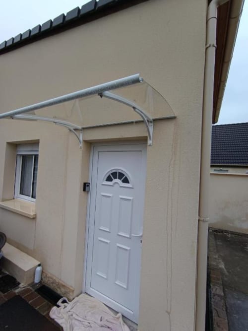 Porte blanche avec imposte et auvent métallique sur la façade beige d'une villa à Pont-Sainte-Maxence