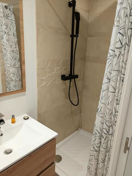 Salle de bain moderne de la villa Pont-Sainte-Maxence avec lavabo blanc, douche à effet pluie et rideau botanique