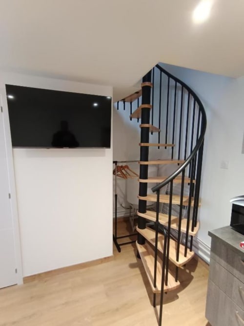 Escalier spiral moderne avec marches en bois et rampe noire dans un espace de vie élégant