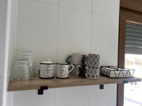 Estante de madera en apartamento salmantino con vasos, azucarero y lechera esmaltados, tazas estampadas y artículos decorativos