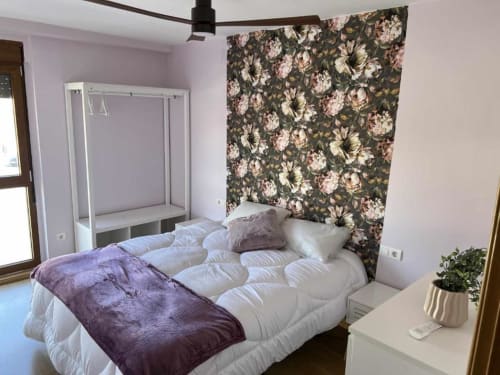 Dormitorio moderno en apartamento AlmaMaterSalamanca con papel tapiz floral, cama dosel y vistas a la ciudad