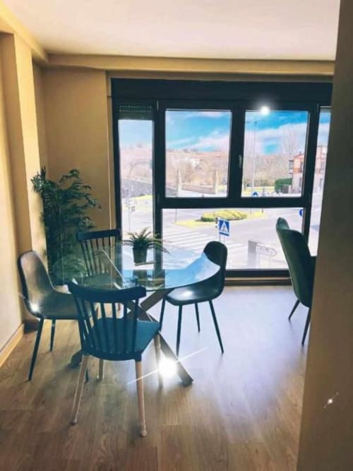 Comedor moderno del apartamento AlmaMaterSalamanca con vistas panorámicas de la ciudad desde ventanales de piso a techo