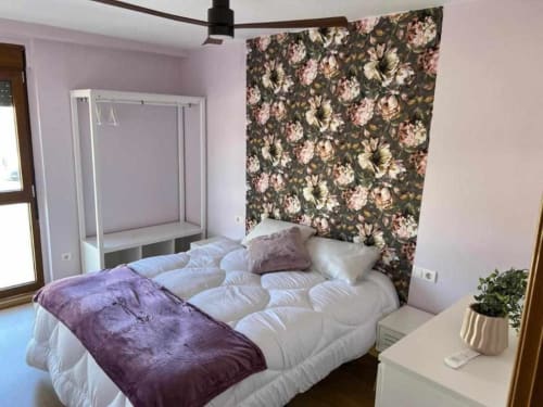 Dormitorio espacioso en Apartamentos AlmaMaterSalamanca con cama con dosel, pared floral y comodidades modernas